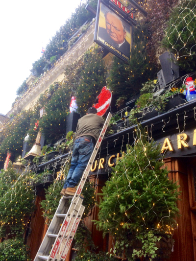 Putting up Christmas decorations at Fuller's pub The Churchill Arms in London