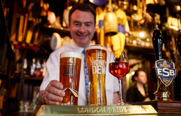 James Keogh Manager of The Churchill Arms pub London serving drinks at the bar